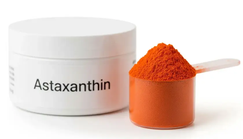 Słoiczek z napisem "Astaxanthin" i miarka pełna pomarańczowego proszku. To właśnie astaksantyna, silny antyoksydant.