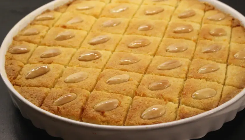 En gyllene basbousa, skuren i rutor och toppad med mandlar. Perfekt för ett enkelt basbousa recept.