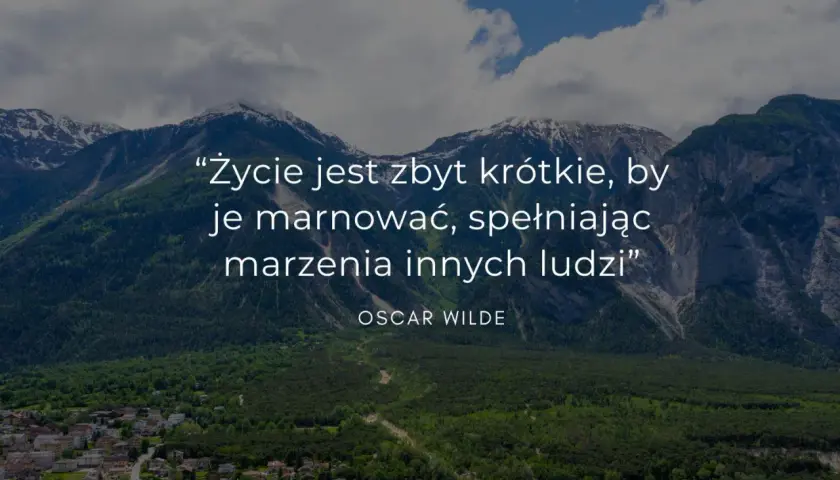 Mądre cytaty krótkie: "Życie jest zbyt krótkie, by je marnować, spełniając marzenia innych ludzi" - Oscar Wilde. Góry i miasteczko w tle.