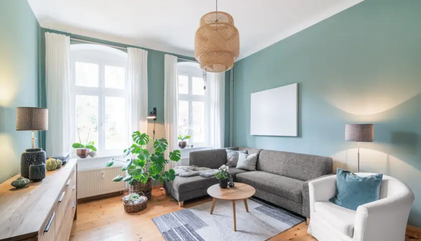 Gemütliches Wohnzimmer mit Sofa, Sessel und Holzboden. Pflanzen und natürliche Materialien schaffen eine harmonische Feng Shui Atmosphäre.