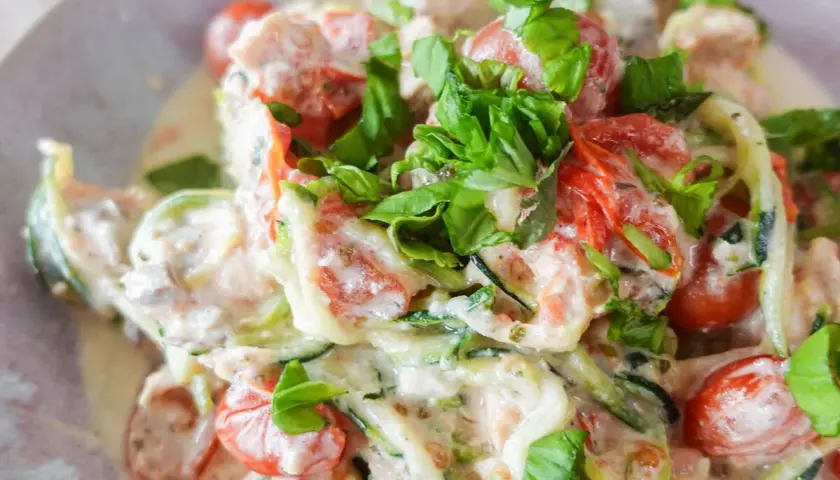 Cremiges low carb lachs Gericht mit Zucchini-Nudeln, Kirschtomaten und frischem Basilikum.
