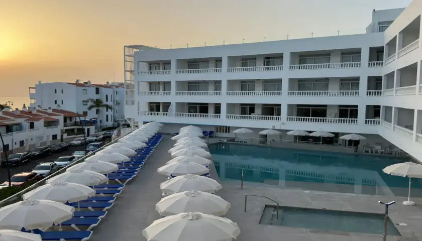 Hotel moderno con piscina y tumbonas, vistas al mar y al atardecer. El azul mar de Lagos de César invita al descanso.