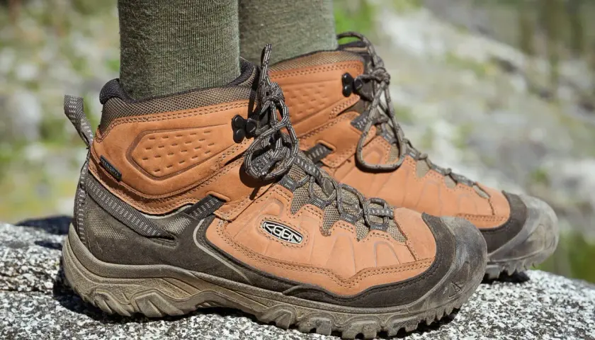 Brown leather hiking boots with green socks. They fit snugly, offering support for any trail.