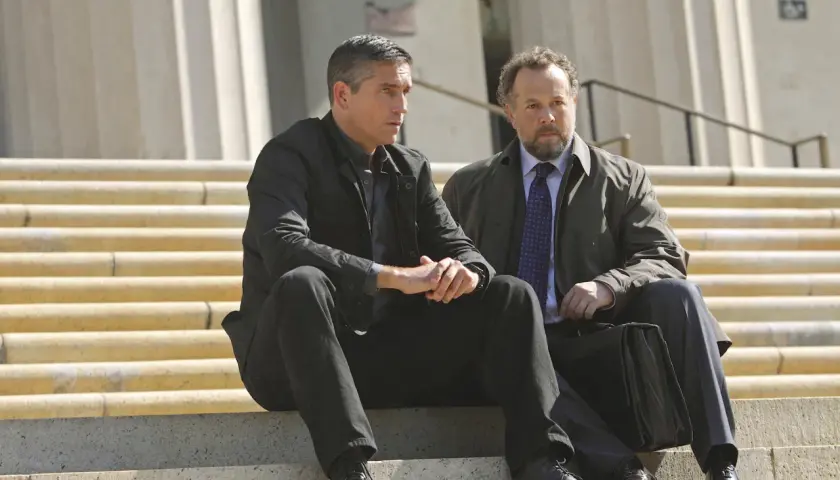 John Reese och Harold Finch från rollistan i Person of Interest sitter på trappsteg.