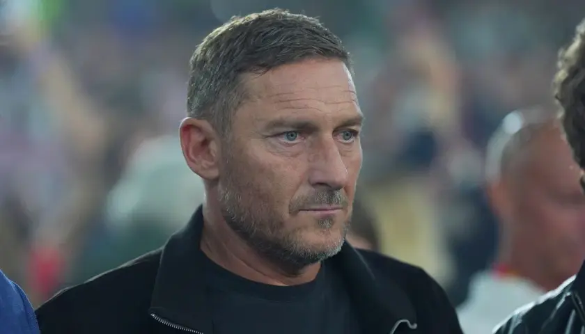 Francesco Totti, legenda piłkarzy z Rzymu, w czarnej kurtce, z uwagą obserwuje wydarzenia.