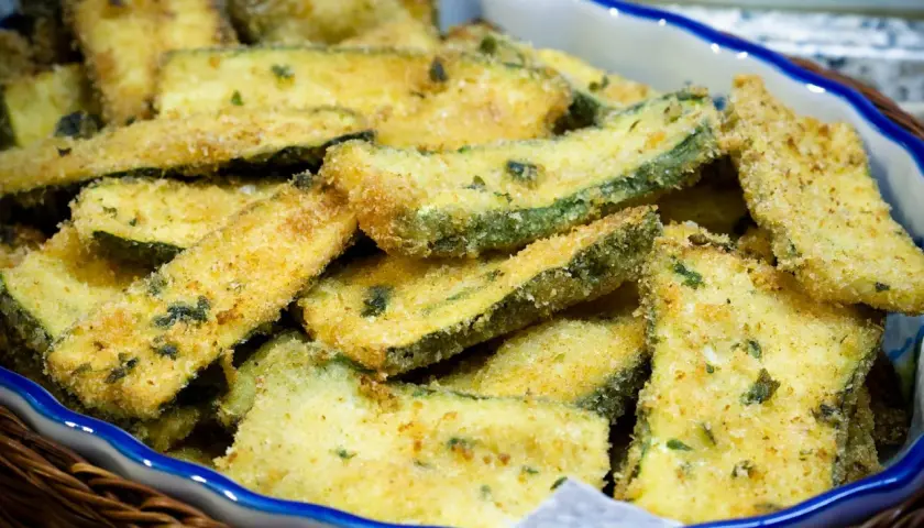 Zucchine gratinate in padella, dorate e croccanti, servite in un cestino di vimini.