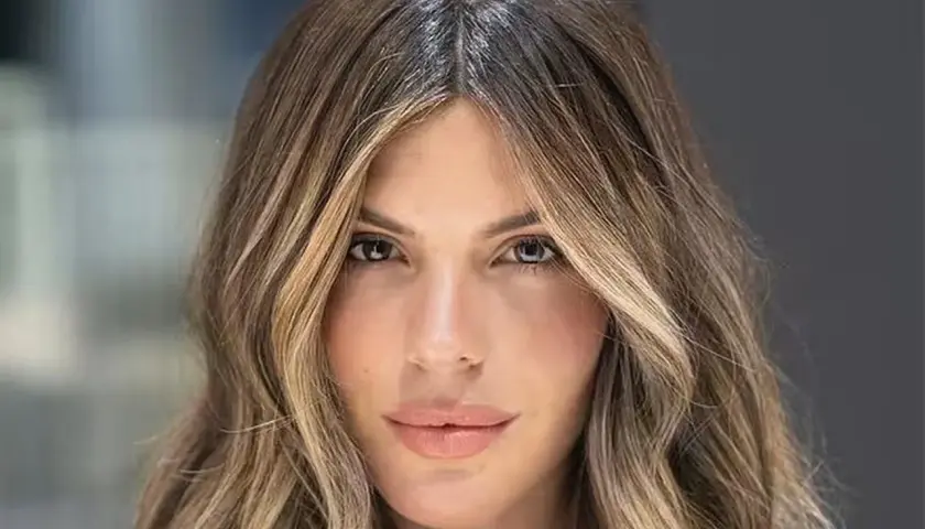 Mujer con pelo castaño con canas y mechas rubias, con ondas suaves y raya en medio.