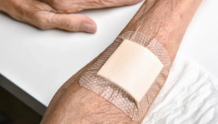 Plaster na odleżyny ze srebrem na przedramieniu osoby starszej. Dbałość o skórę i komfort.
