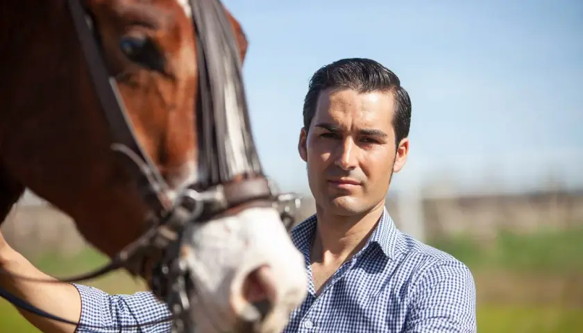 Alberto Sandoval, picador, posa junto a un caballo castaño con brida.