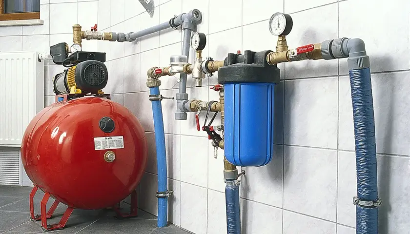 System hydroforowy z pompą, czerwonym zbiornikiem i niebieskim filtrem wody. Rury i złączki pex tworzą skomplikowaną instalację.