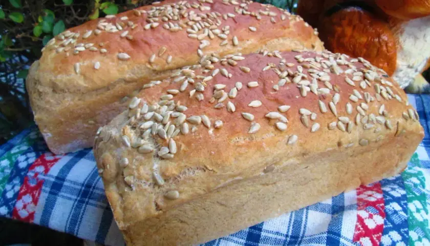Dwa bochenki domowego chleba posypane słonecznikiem, idealne do nauki jak upiec chleb w domu.
