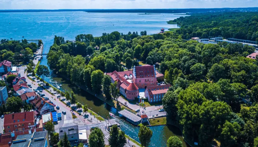 Malowniczy hotel na Mazurach, otoczony zielenią i wodą, z widokiem na jezioro. Idealne miejsce na wypoczynek.