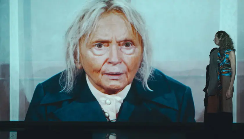 Na ekranie twarz starszej kobiety, w tle młoda kobieta. To scena z przedstawienia "święta Liliana".