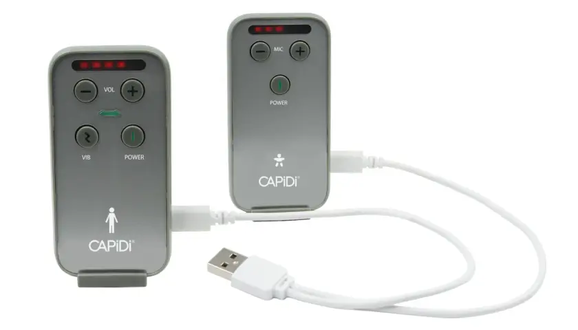 Två grå enheter med texten CAPIDI och knappar för volym, mikrofon, vibration och ström. En vit USB-kabel kopplar ihop dem. En trygghet med capidi babyalarm.