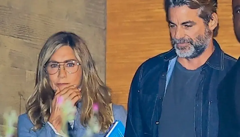 Jennifer Aniston z partnerem, w okularach, z telefonem i książką w ręku, obok mężczyzny z siwą brodą.