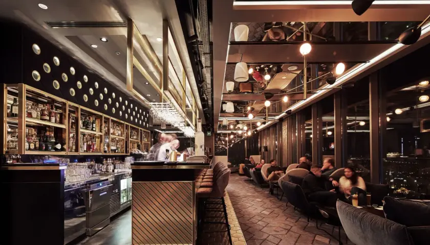 Elegancki bar i wygodne fotele tworzą klimatyczne restauracje Katowice. Goście relaksują się przy widoku na nocne miasto.