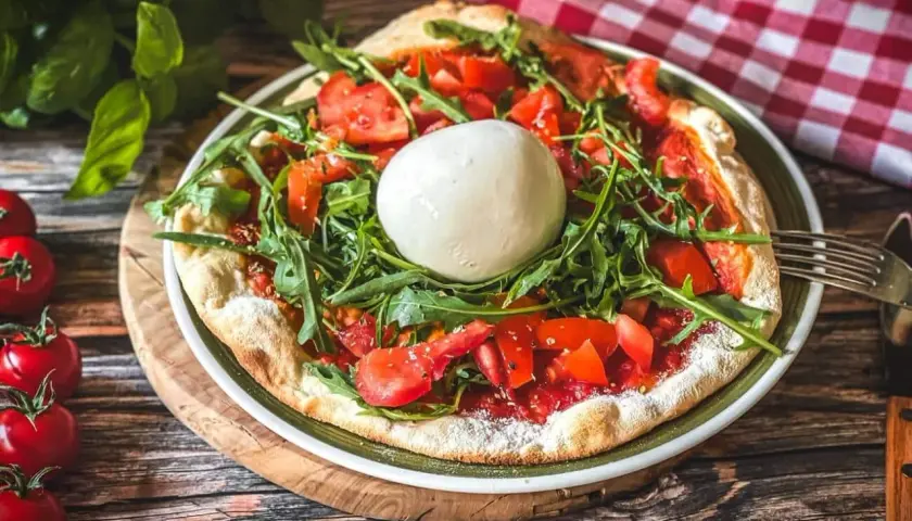 Pizza mit frischen Tomaten, Rucola und einer Kugel Burrata, die Lust auf burrata selber machen macht.