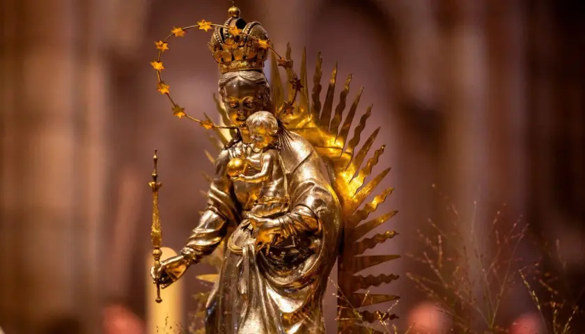 Goldene Statue der Maria mit Kind, gekrönt und von Strahlen umgeben. Die Bedeutung von Maria wird hier durch ihre königliche Darstellung und die Verehrung deutlich.