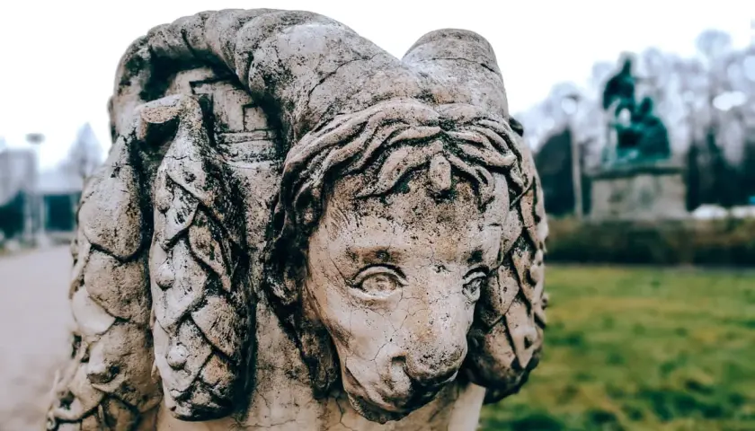 Kamienna rzeźba z wyrytymi imionami demonów, przypominająca lwa z rogami.