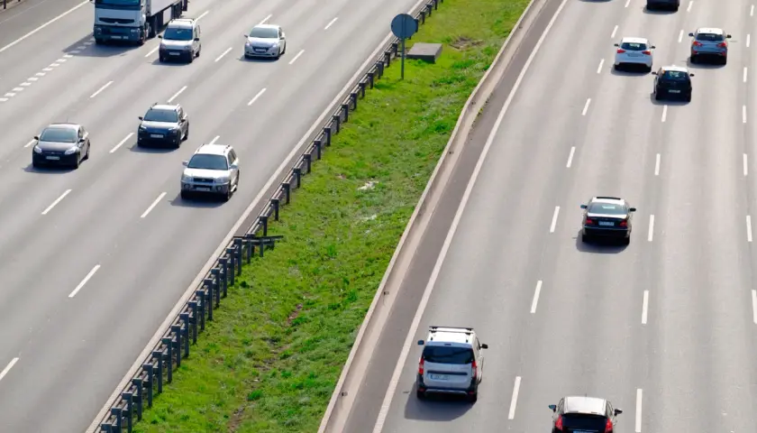 Varios coches circulan por la autopista. Un camión blanco lidera el tráfico. ¿Es correcto este adelantamiento?