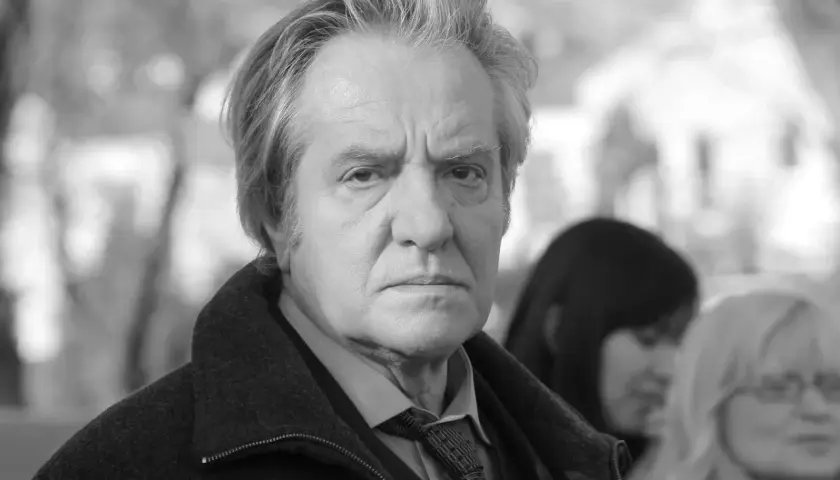 Jerzy Grałek, aktor, w czarnym płaszczu i krawacie, zamyślony.