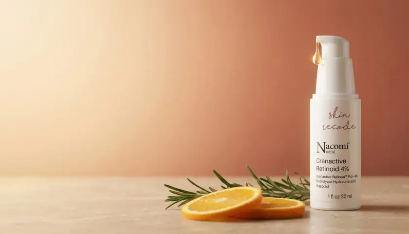 Retinol na twarz efekty: biała buteleczka serum z pompką, plasterki pomarańczy i gałązka rozmarynu.