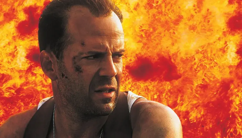 Bruce Willis i en actionfylld scen, med eld bakom sig. En klassisk bild från filmer med Bruce Willis.
