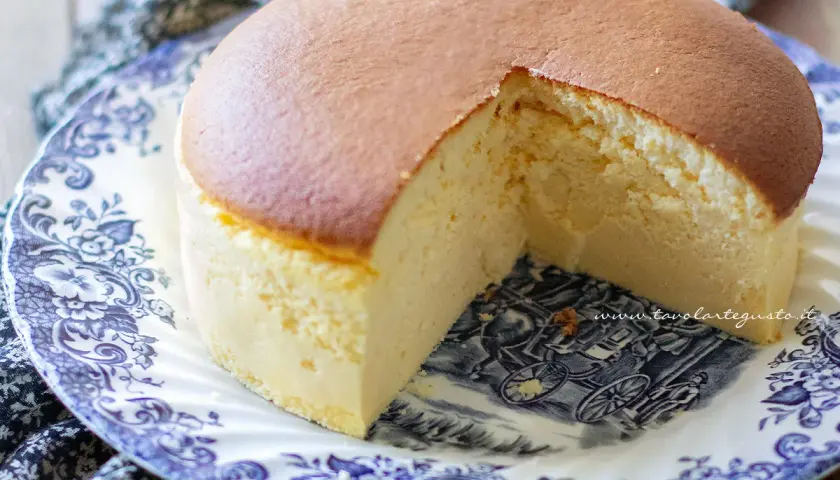 Una soffice torta giapponese, dorata in superficie e chiara all'interno, servita su un piatto decorato con un paesaggio in stile antico.