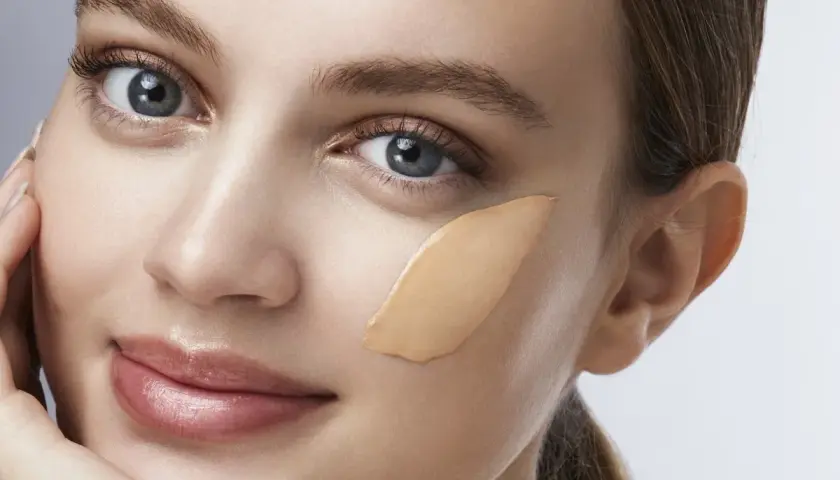 Una donna con un tocco di fondotinta sulla guancia, pronto per essere sfumato.