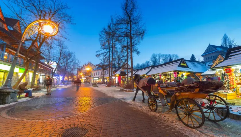 Wieczorny spacer po Krupówkach, gdzie zakopiańskie centrum kultury tętni życiem. Konny zaprzęg i oświetlone kramy tworzą magiczny klimat.