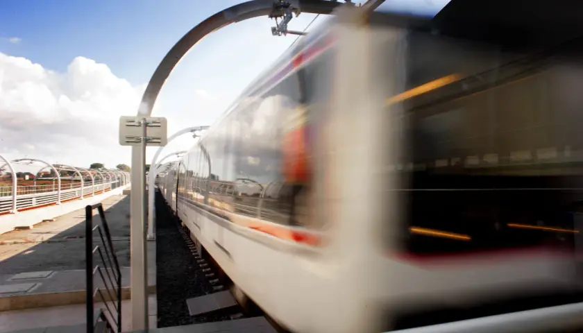 Treno in corsa sulla borghesiana metro c, con riflessi nel cielo e luci interne.