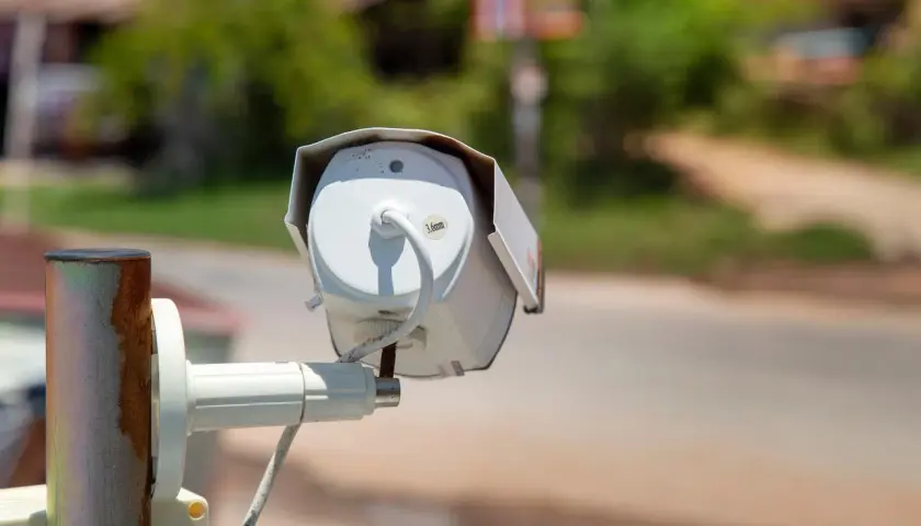 Kamera do monitoringu domu, zamontowana na zardzewiałym słupku, czuwa nad otoczeniem.