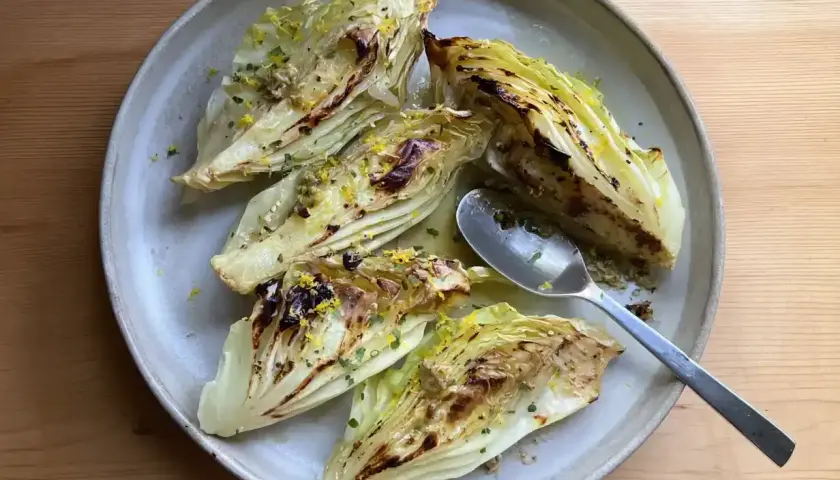 Grillad spetskål med citron och örter på en ljusgrå tallrik. En sked ligger på tallriken.