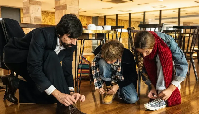 Padre e figli si allacciano le scarpe, un momento di vita quotidiana che merita recensioni positive per la sua semplicità.