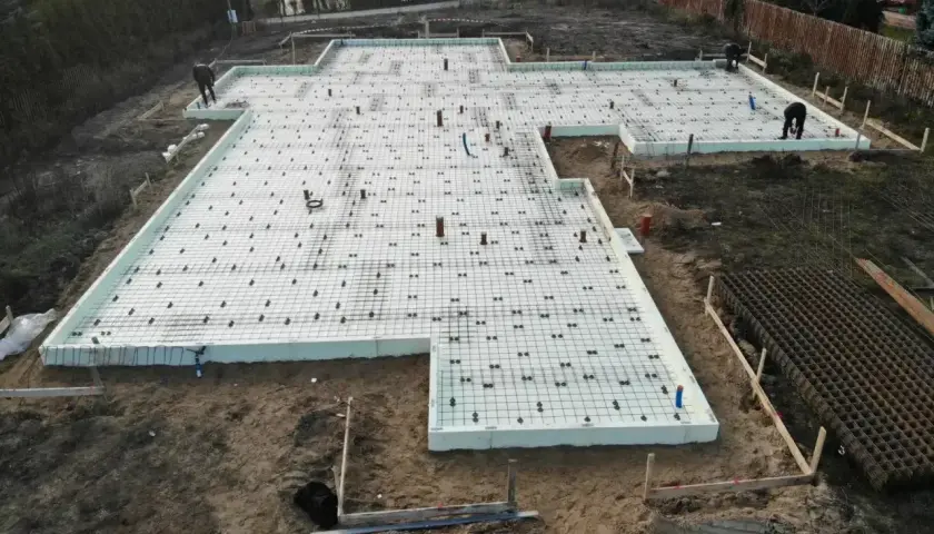 Fundament pod budowę z siatką zbrojeniową i rurami. Szybki beton zostanie wkrótce wylany na tę przygotowaną powierzchnię.