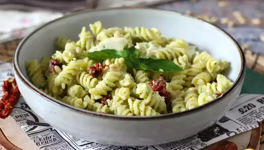 Un plat de pâtes fusilli au pesto, tomates séchées et pignons de pin. Une idée parfaite pour savoir que faire avec un reste de pâtes !