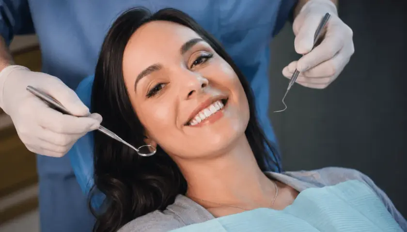 Uśmiechnięta pacjentka u dentysty, która mimo narzędzi nie wykazuje odruch wymiotny.