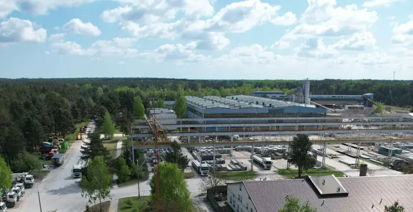 Fabryka domów Bogucin z lotu ptaka. Widok na hale produkcyjne, place składowe z elementami prefabrykowanymi i ciężarówki.