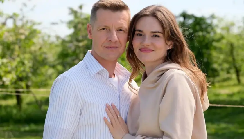 Para, która zastanawia się, ile odcinków ma M jak Miłość, pozuje na tle zieleni.