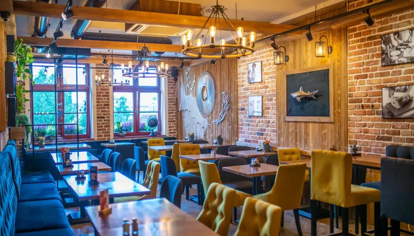 Przytulne wnętrze z ceglanymi ścianami i drewnianymi elementami, idealne na odkrycie najlepszych restauracji w Sopocie.