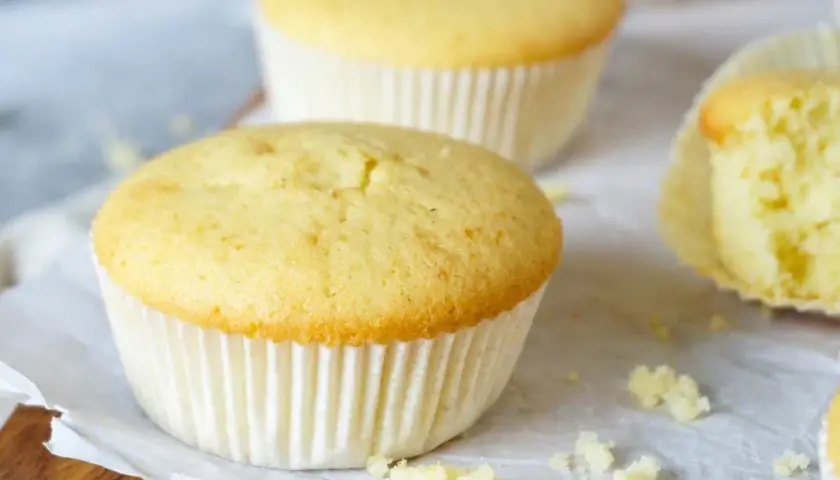 Zarte Muffins, perfekt für das Muffins Grundrezept. Einer ist angeschnitten und zeigt die fluffige Textur.