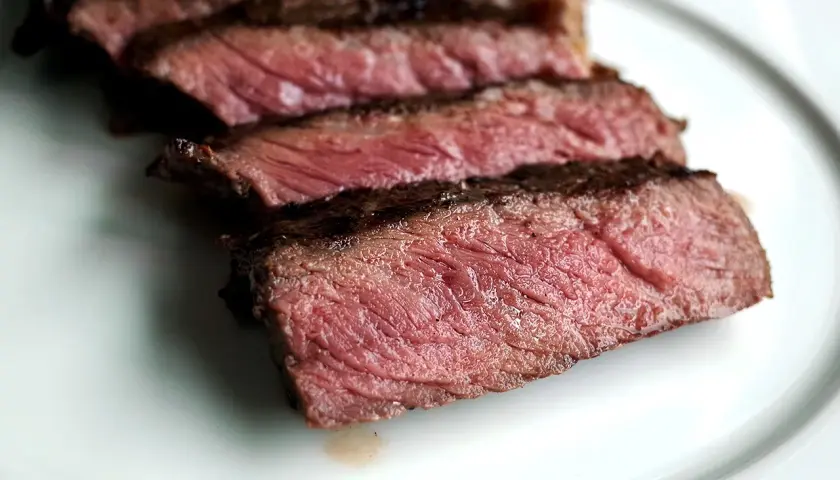 Tranches de bœuf bleu blanc belge, juteuses et saignantes, sur une assiette blanche.