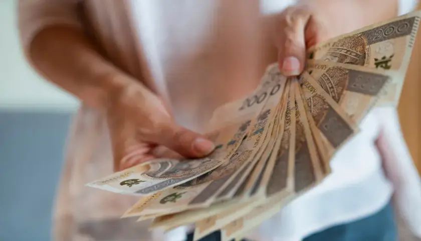Dłonie trzymają wachlarz banknotów 200 zł. To symbol nagrody jubileuszowej za 40 lat pracy w budżetówce, zasłużone docenienie wieloletniego trudu.