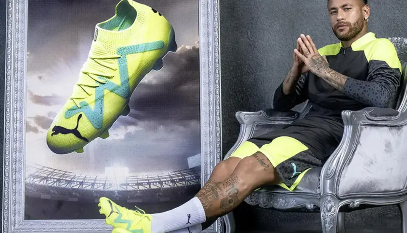 Neymar w neonowych butach piłkarskich Puma, idealnych na sztuczną trawę, siedzi na tronie.