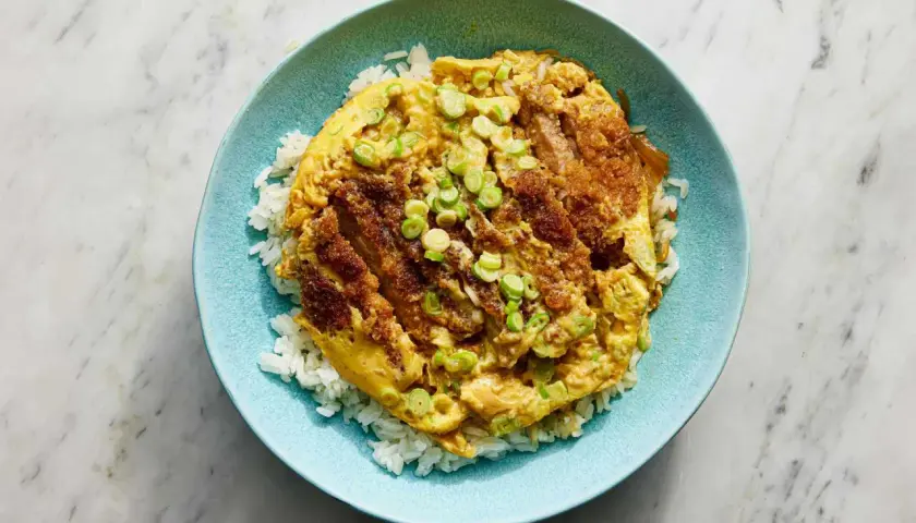 A delicious katsu donburi recipe, featuring crispy fried pork cutlet over fluffy white rice, topped with a savory egg and green onions.
