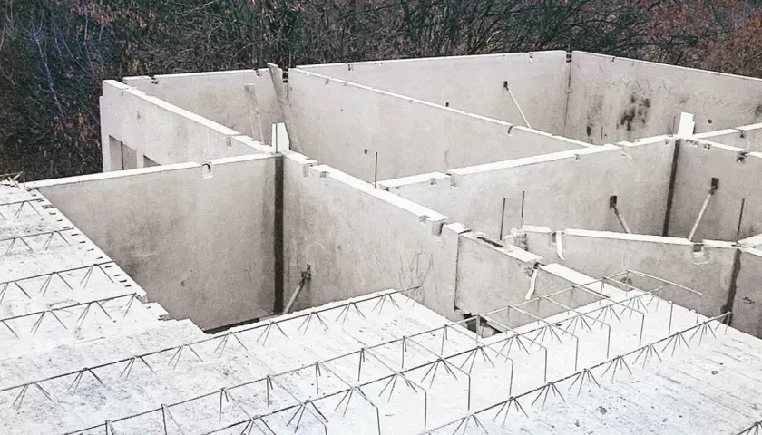 Budowa domu w toku. Widać betonowe ściany i przygotowany do wylania strop filigran z siatką zbrojeniową.