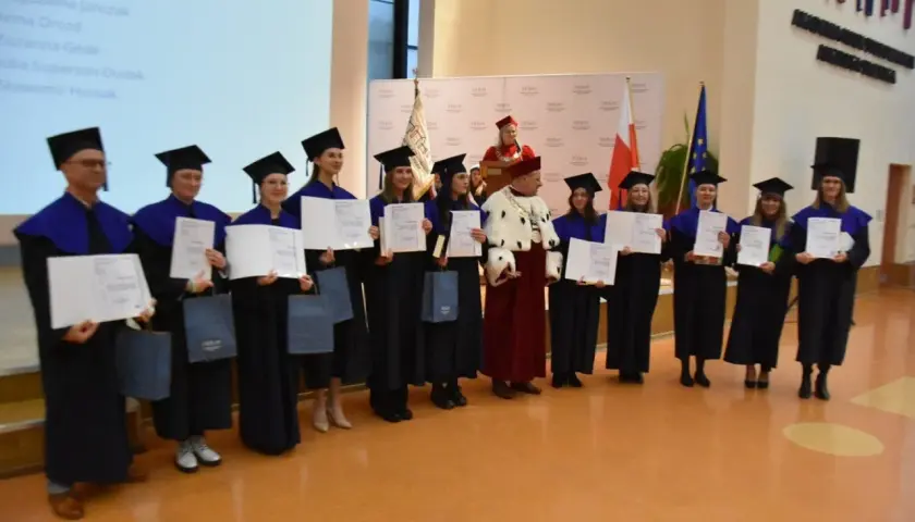 Absolwenci w togach i biretach odbierają dyplomy. Uroczystość wręczenia tytułów licencjat.