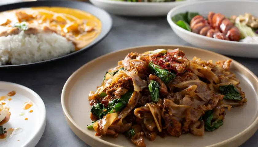 Talerz z makaronem ryżowym, mięsem i zielonymi warzywami, ozdobiony chili.