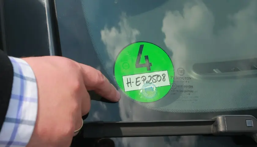 Palec wskazuje na zieloną winietę z numerem 4 i rejestracją H-EP2508, naklejoną na przedniej szybie samochodu w Niemczech.