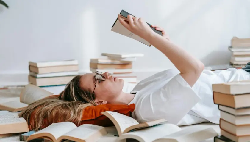 Dziewczyna leży wśród książek, zastanawiając się nad różnicą między retellingiem baśni a klasyczną adaptacją literacką.